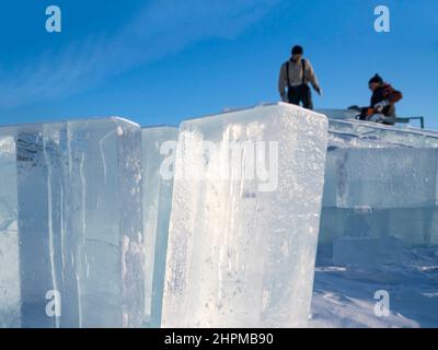 Realizzare sculture di ghiaccio. Gli uomini livellano la superficie nel ghiaccio con una sega a benzina sul lago Baikal. Foto Stock