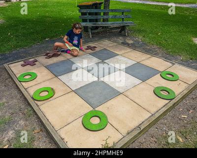Una ragazza gioca Tic TAC Toe (Noughts and Crosses) su un grande asse presso la fattoria e parco divertimenti di Amazement, Yarramalong, Central Coast, NSW, Australia Foto Stock