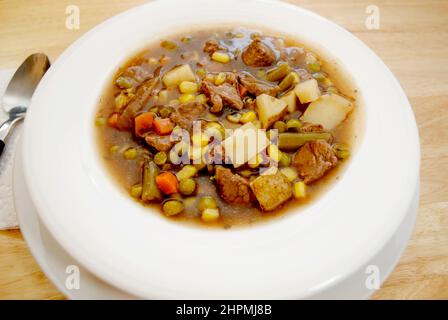 Stufato di manzo abbondante servito in un recipiente bianco, primo piano Foto Stock