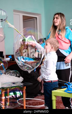 Dolyna, Ucraina 28 maggio 2021: Animatori e bolle di sapone per una vacanza dei bambini, un ragazzo che fa una bolla grande da solo, uno spettacolo divertente e divertente. Foto Stock