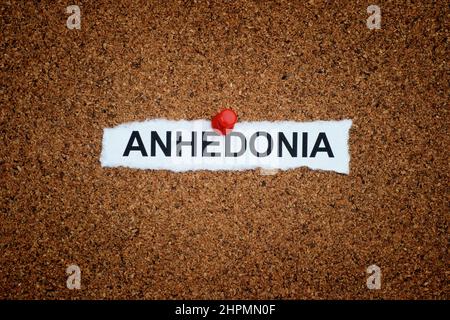 Un pezzo di carta stropicciato con la parola anhedonia su di esso fissato ad un bordo. Primo piano. Foto Stock