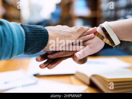 Heres a diritto come. Scatto ritagliato di un gruppo di studenti che si accatastano le mani l'una sull'altra. Foto Stock