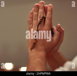 La fede troverà la risposta. Scatto corto di un uomo che tiene un rosario e prega. Foto Stock