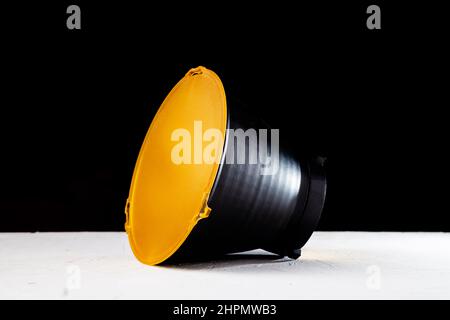 Riflettore standard con diffusore giallo opaco su sfondo nero. Attacco per flash studio con supporto bowens. Foto Stock