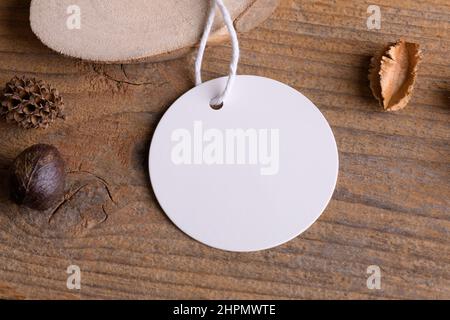 Tondino bianco mockup tag su un rustico sfondo di legno con filo di cotone e decorazione boho, elemento per imballaggio, primo piano. Etichetta prodotto bohémien moc Foto Stock