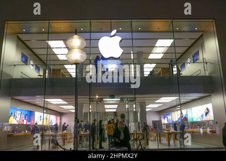 Apple store Monaco con clienti, negozio illuminato, shopping serale. Foto Stock