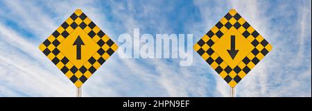 Segnaletica stradale con frecce di direzione su e giù affiancate contro un suggestivo cielo blu Foto Stock