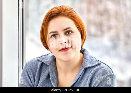 Pettorina con capelli colorati di rosso dalla giovane donna europea all'interno. Foto Stock