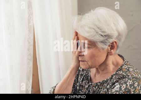 grannia heartbroken che soffre di demenza che tocca il suo viso con un palmo medio primo piano. Foto di alta qualità Foto Stock
