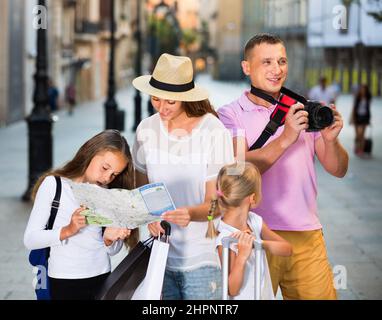 Famiglia turistica che usa la mappa e scatta foto della città mentre passeggi Foto Stock