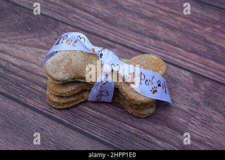 Dolci fatti in casa per cani "a forma di osso" avvolti in un nastro a tema per animali domestici. Foto Stock