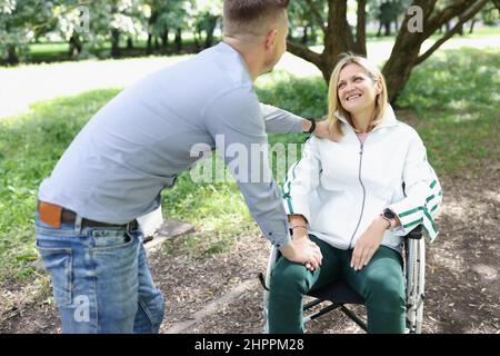 Il giovane comunica con la donna in sedia a rotelle Foto Stock