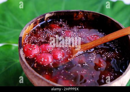 Vista dall'alto fragole rosse zuccherate in ciotola che fanno da conchiglie di cocco su foglia verde, frutta rossa fresca da Lat per giorno d'estate, cibo yummy Foto Stock