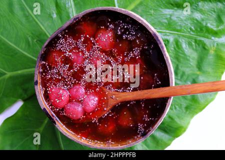 Vista dall'alto fragole rosse zuccherate in ciotola che fanno da conchiglie di cocco su foglia verde, frutta rossa fresca da Lat per giorno d'estate, cibo yummy Foto Stock