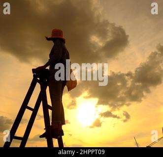 Scena stupefacente da donna vietnamita quando rimanere a casa da sociale distanziamento, si fa il divertimento al tramonto sul tetto da stand sulla scala quando il sole scende a m Foto Stock