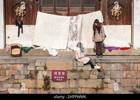 Due giovani donne che chiacchierano su un molo lungo un canale nel villaggio acquatico di Wenzhou, Cina. Foto Stock