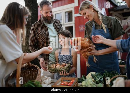 Felice womanl acquisto di uova biologiche all'aperto al mercato contadino della famiglia locale. Foto Stock