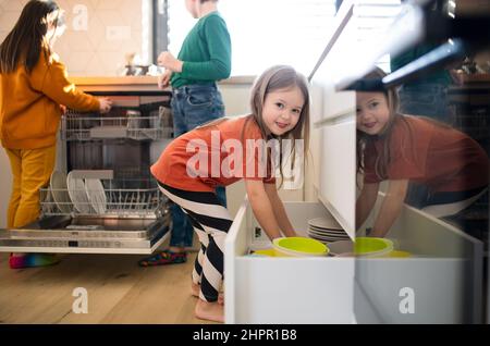 Tre piccoli chidlren aiutare con i piatti in cucina a casa. Foto Stock