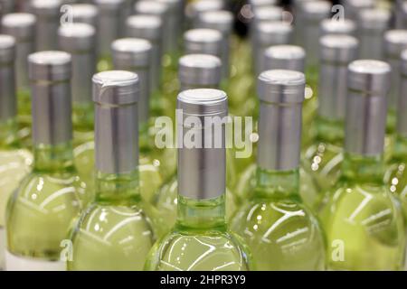 Bottiglie di vino bianco in fila, fuoco selettivo. Negozio di liquori, produzione di vino Foto Stock
