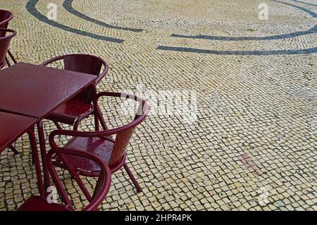 Tavoli e sedie di un caffè di strada in una giornata piovosa a Lisbona, Portogallo. Messa a fuoco selettiva Foto Stock