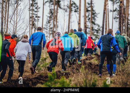 atleti di gruppo che camminano in salita su sentiero sporco in gara di maratona Foto Stock