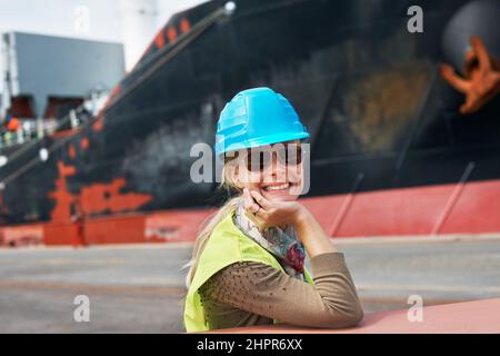 Il mio atteggiamento non deve mai essere soddisfatto. Una giovane donna fiduciosa che riposa il mento sulle mani accanto a una nave. Foto Stock