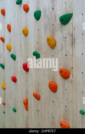 l'arrampicata colorata si tiene su un muro di legno Foto Stock