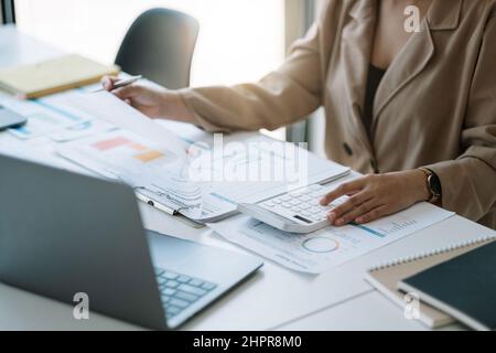 Primo piano bilancio di pianificazione della donna, utilizzando calcolatore e laptop, lettura di documenti, giovane donna controllo finanze, conteggio fatture o tasse, online Foto Stock