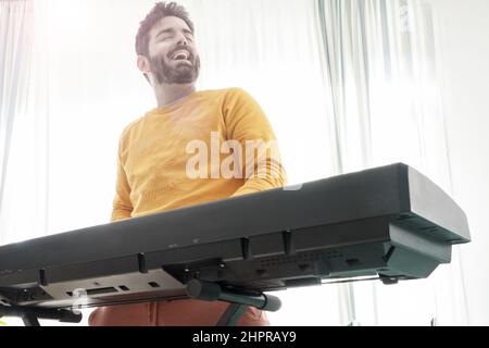 middle aged young man have fun playing  with digital piano at home Foto Stock