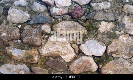 Tradizionale vecchio muro di pietra con motivi di muschio. Vista frontale e primo piano. Foto Stock