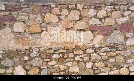 Muro di pietra costruito in tempi diversi. Due diverse strutture di pareti in pietra. Foto Stock