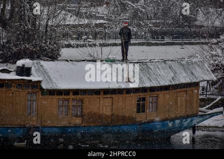 Kashmir, India , 23/02/2022, Srinagar, India. 23rd Feb 2022. Un uomo libera la neve dalla sua houseboat durante la nevicata pesante in Srinagar.la maggior parte delle zone della valle del Kashmir il mercoledì ha ricevuto nevicate - la prima caduta pesante della stagione nelle pianure - interrompendo il volo e le operazioni ferroviarie e portando alla chiusura della vitale Srinagar-Jammu strada nazionale, funzionari qui ha detto. Credit: SOPA Images Limited/Alamy Live News Foto Stock