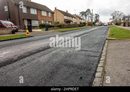 Una strada di recente ripavimentazione con asfalto fresco posato sulla superficie stradale esistente a Reading, Regno Unito. Foto Stock