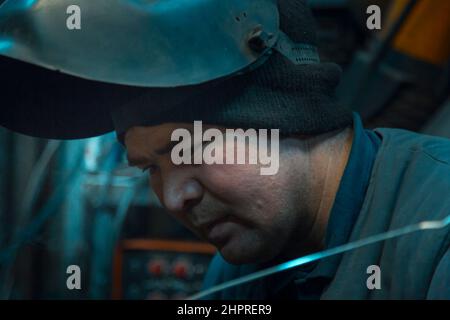 Ritratto di una saldatrice ad arco in argon con casco la testa sul posto di lavoro Foto Stock