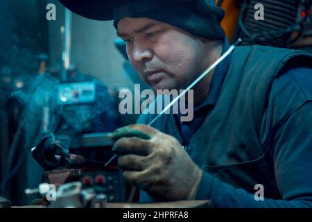 Ritratto di una saldatrice ad arco in argon con casco la testa sul posto di lavoro Foto Stock