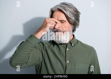 Ritratto di attraente stanco depresso malato uomo grigio-pelato toccare naso che soffre isolato su sfondo grigio color pastello Foto Stock