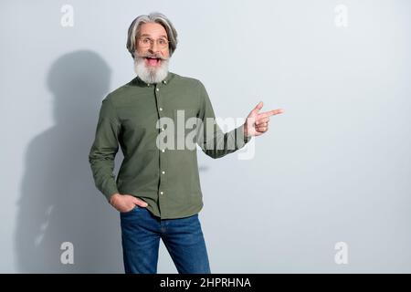 Ritratto di attraente allegro stupito uomo grigio-capelli dimostrazione spazio copia nuovo annuncio isolato su sfondo grigio color pastello Foto Stock
