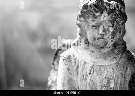 Angelo in preghiera con dolce espressione facciale. Immagine in bianco e nero di un'antica statua in pietra. Spazio di copia. Foto Stock