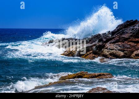 Una grande onda colpisce le rocce ed esplode in un grande spruzzo. Foto Stock