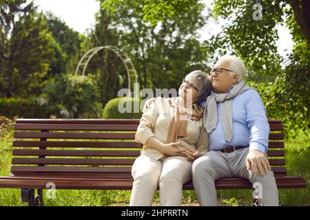 Romantica coppia anziana amorevole seduta su panchina e abbracciata nel parco Foto Stock