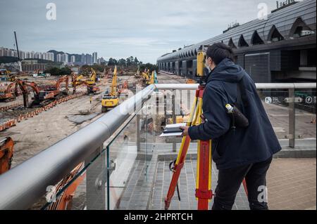 Hong Kong, Cina. 23rd Feb 2022. Un topografo effettua le misurazioni presso il sito di costruzione della quarantena del terminal delle navi da crociera Kai Tak. In tutta Hong Kong si stanno costruendo nuove stazioni di quarantena comunitarie per accogliere il crescente numero di persone che hanno dato risultati positivi al COVID-19. Con una politica per isolare, trattare e, se necessario, ricoverare tutti i pazienti COVID-19 e stretti contatti, il governo di Hong Kong sta creando oltre 10.000 nuovi spazi per l'isolamento e il trattamento. Credit: SOPA Images Limited/Alamy Live News Foto Stock