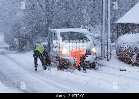 I lavoratori del mattino si sono bloccati nella neve che sgombrano via dal camion che è bloccato su una leggera collina a Killearn, Stirling, Scozia, Regno Unito Foto Stock