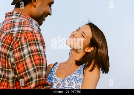 Giovane coppia multirazziale sorridente e abbracciante all'aperto Foto Stock