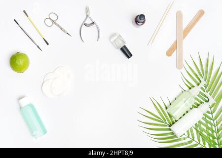 Cura delle unghie. Stendere piano manicure o pedicure strumenti su tavola bianca con foglie verdi. Foto Stock