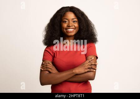 Ritratto di bella femmina nera sorridente in piedi con le braccia piegate Foto Stock