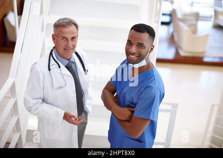 Condividete con noi i vostri problemi di salute. Ritratto di un medico fiducioso e chirurgo in piedi in una suite medica. Foto Stock