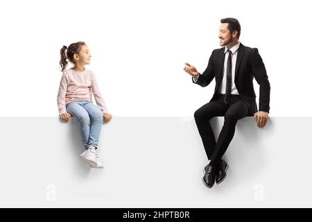 Uomo d'affari seduto su un pannello vuoto e parlare con una bambina isolata su sfondo bianco Foto Stock