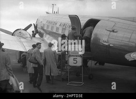 1940s, passeggeri maschi storici, diversi cappotti impermeabili e cappelli, imbarco su un velivolo Douglas DC-3 della Finnish Airlines, all'aeroporto di Helsinki, Finlandia. Foto Stock