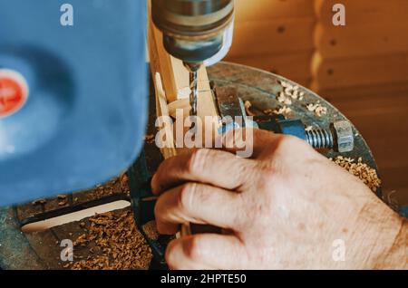 Foratura su tavola di legno. Realizzazione di gambe in legno per cavalletti. Lavori di Falegnameria. Mani di maestro in alto da vicino. Foto Stock