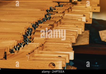 Vista delle gambe di legno ai cavalletti che si trovano in fila. Produzione di cavalletti. Officina di lavorazione del legno. Foto Stock